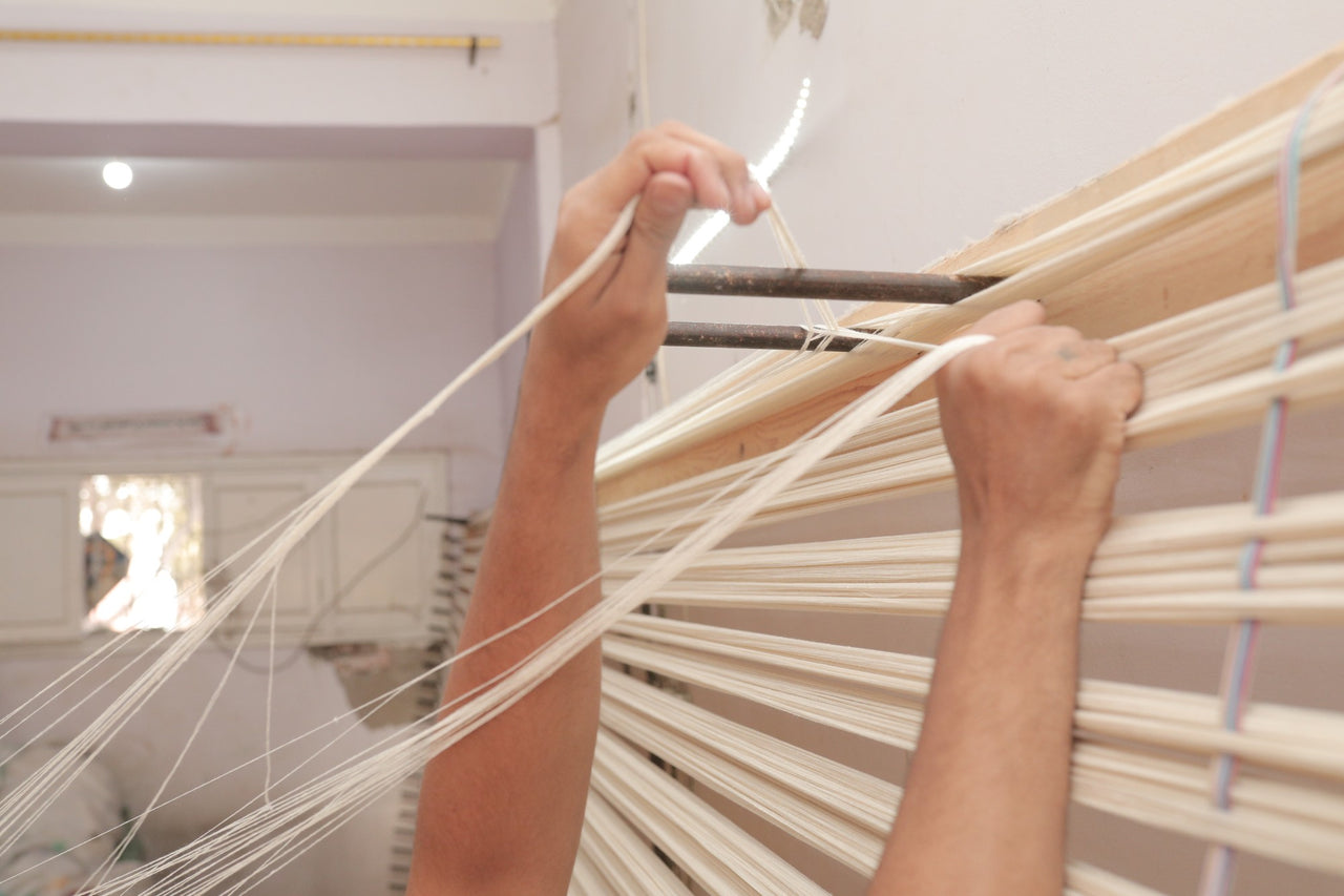 An artisan in Akhmim arranging warp threads on a wooden loom frame